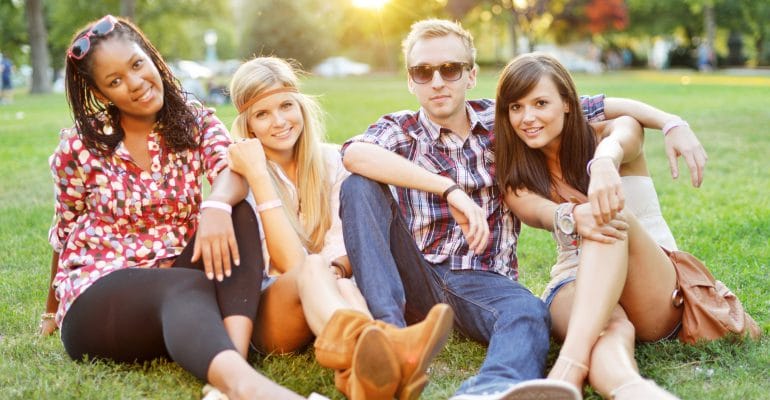 Young beautiful college students sitting together on the grass for a picnic.