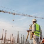 A construction surveyor standing outside at a construction location
