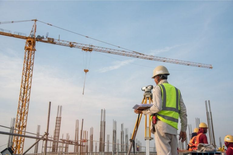A construction surveyor standing outside at a construction location