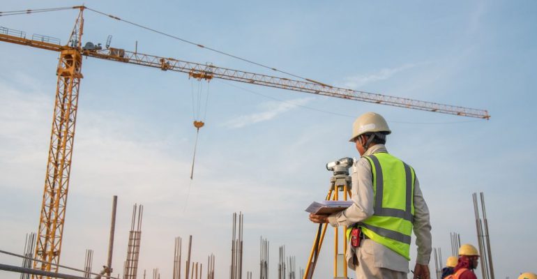 A construction surveyor standing outside at a construction location