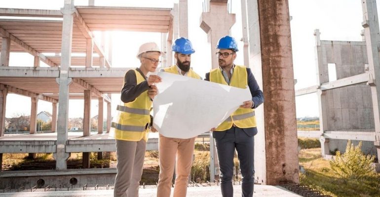 A team of construction managers look over building plans on-site