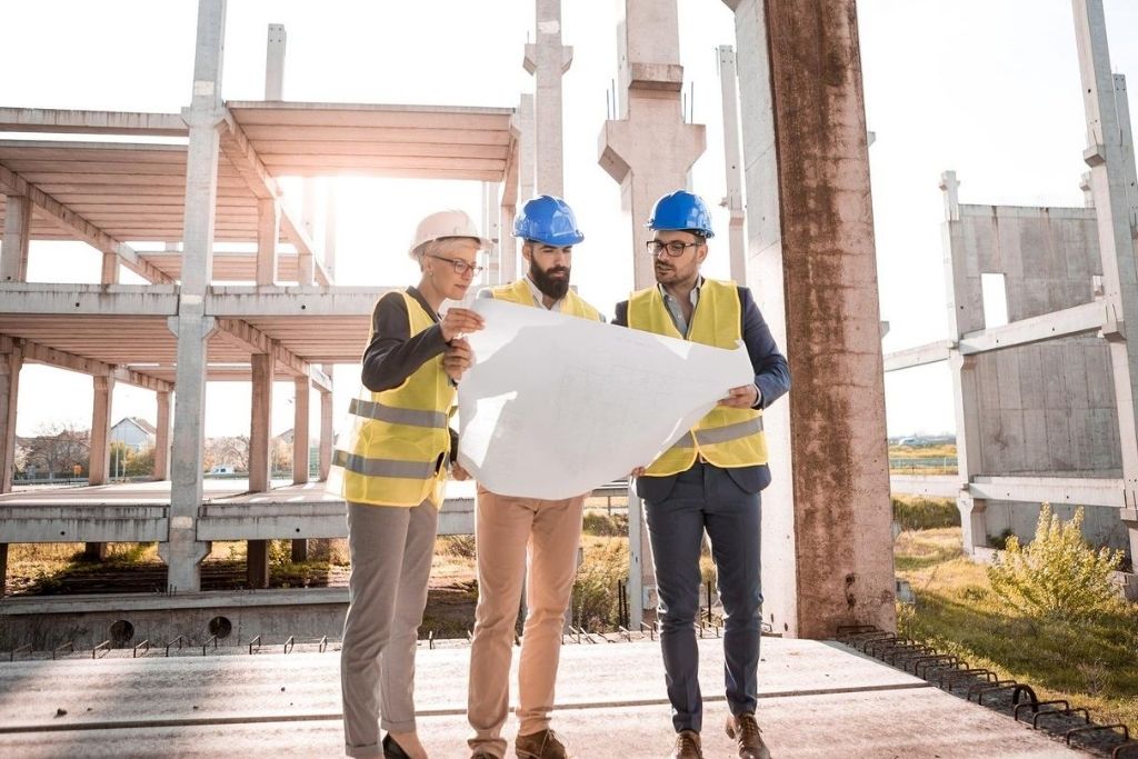 A team of construction managers look over building plans on-site