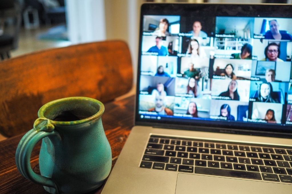 A laptop sitting next to a cup of coffee shows an online meeting platform