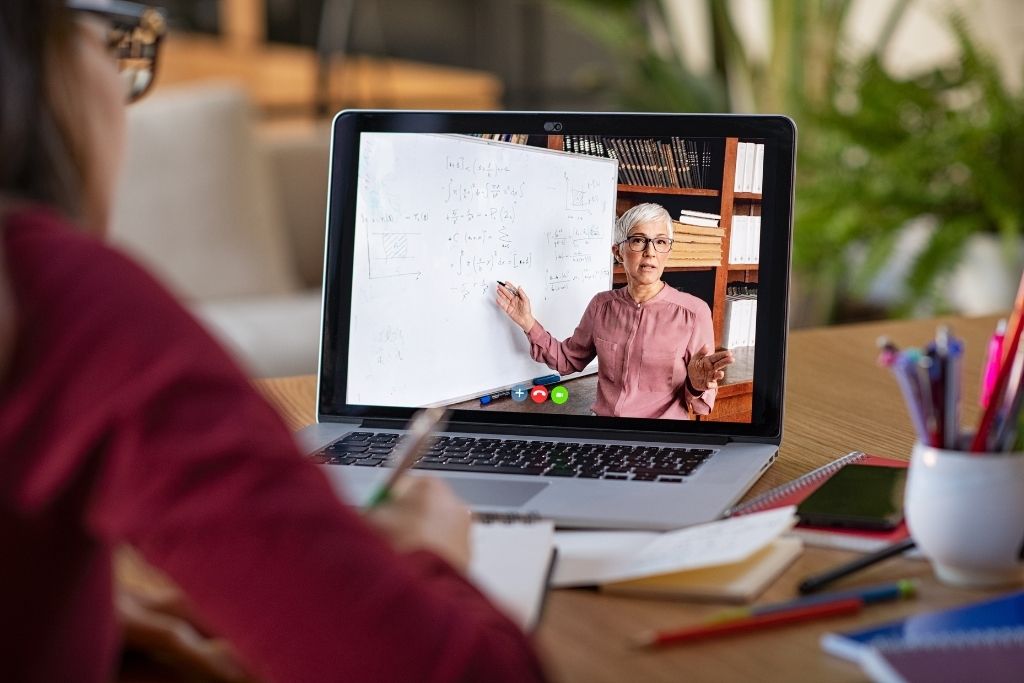 A female student watches a professor online teach a hospitality degree course