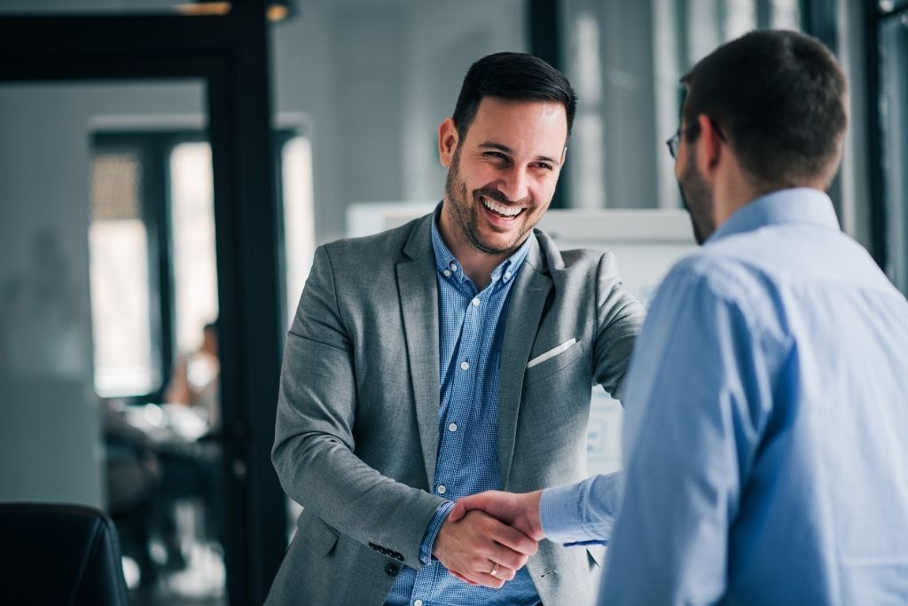 Two men dressed in business attire, shaking hands.