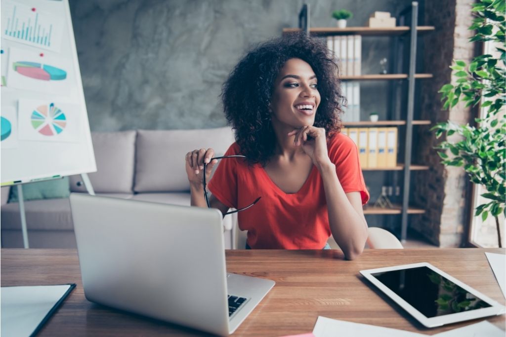 A young female entrepreneur at a table with a laptop and tablet.