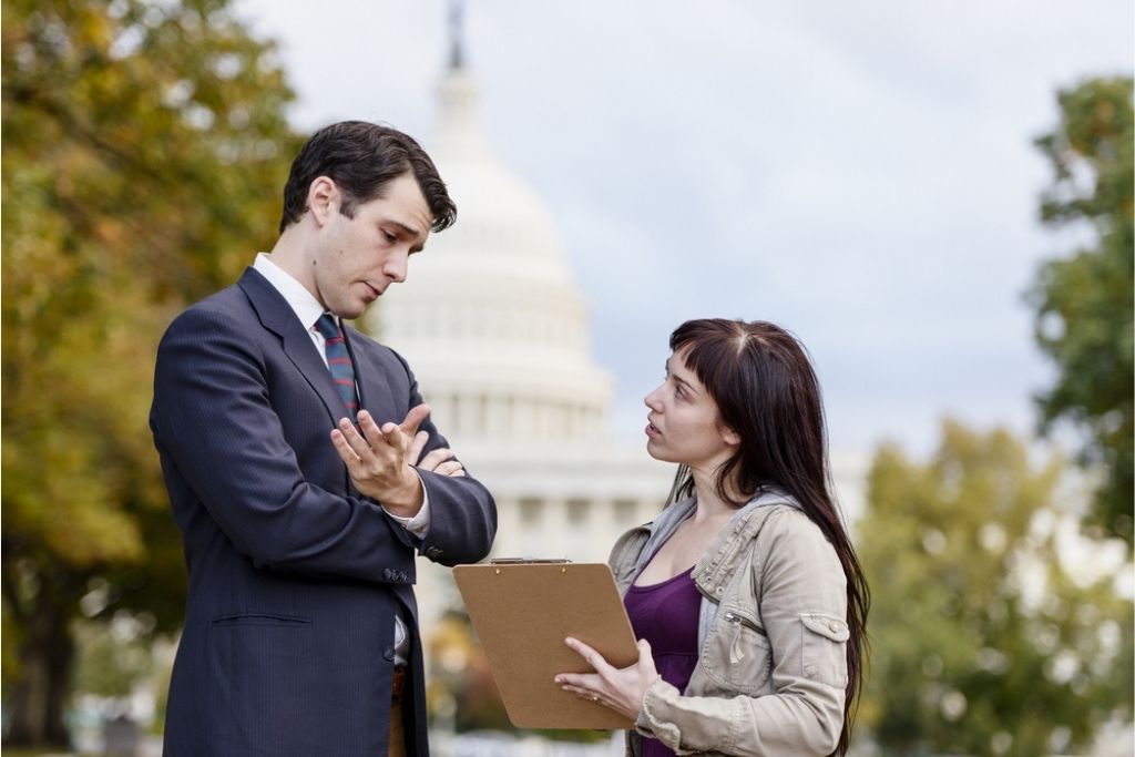 An environmental lobbyist speaks to a politician outside the capitol