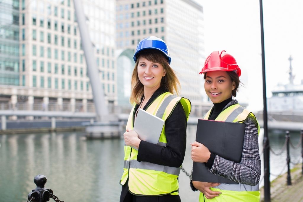 Two female construction management students hold tablets while working on a job site.