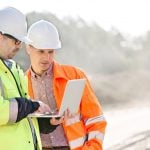 Two male construction managers looking at a laptop