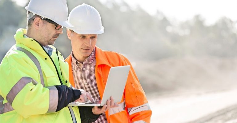 Two male construction managers looking at a laptop