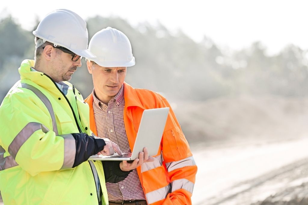 Two male construction managers looking at a laptop