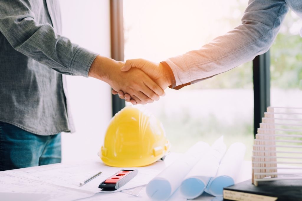 A newly hired construction manager shakes hands with an employer at an interview