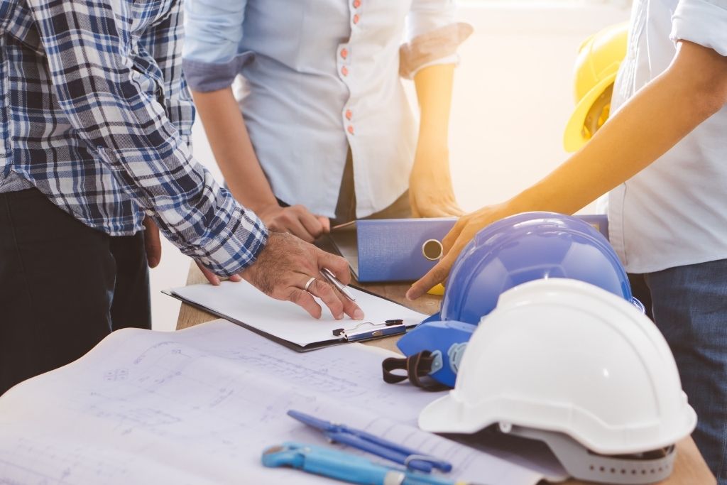 Team around a table with hardhats and paperwork.