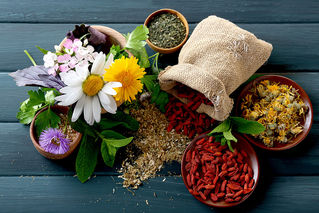 Flowers, plants, herbs, and fruits in bowls on a wooden table alternative medicine schools