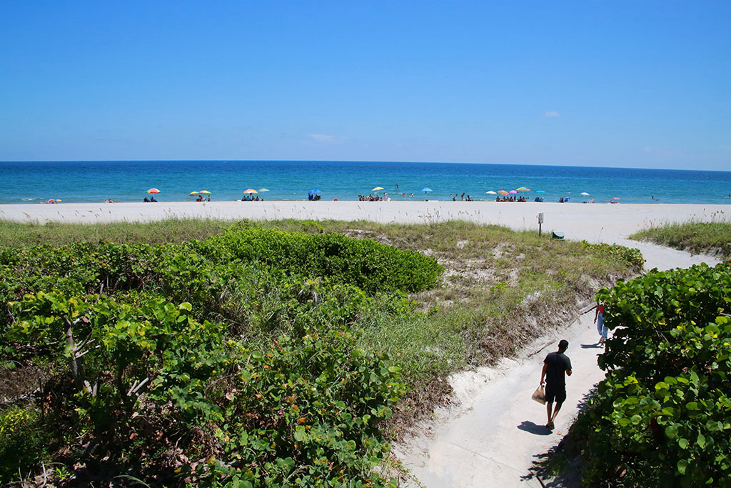 A man walks down a sandy path to Spanish River Beach Park in Boca Raton, Florida