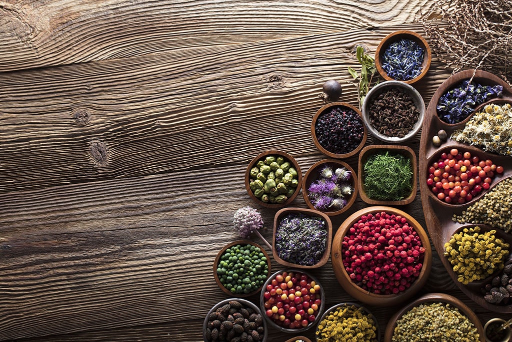 An assortment of herbs, seeds, fruits, and vegetables on a wooden table