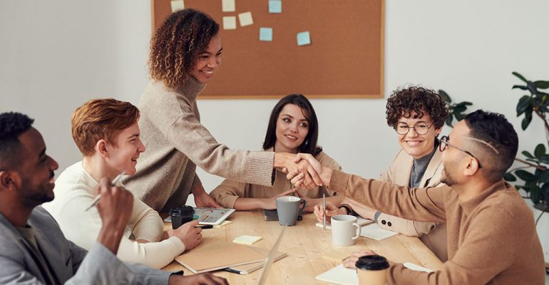 A female human resource manager meets with employees and shakes hands with a male employee