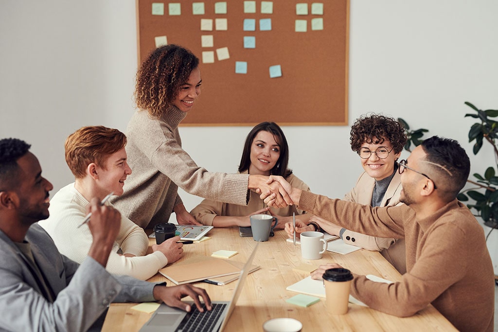 A female human resource manager meets with employees and shakes hands with a male employee