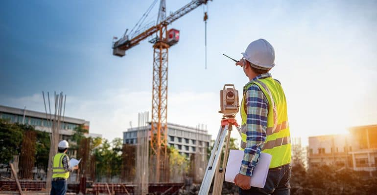 Man using survey equipment on a construction site.