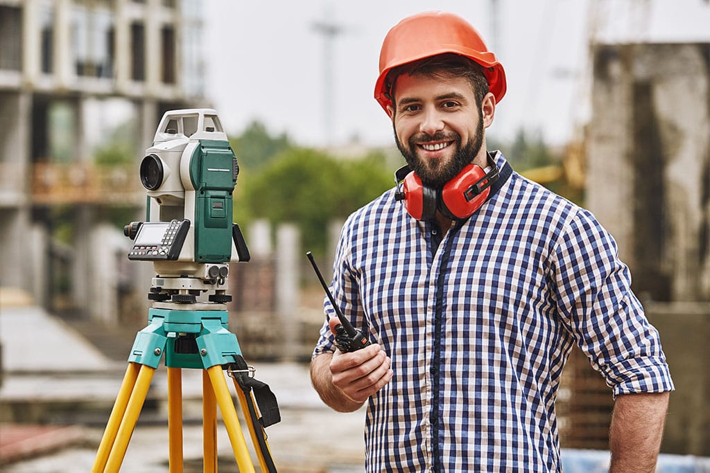 Man with a hard hat and protective gear on a construction site within the Surveying Industry