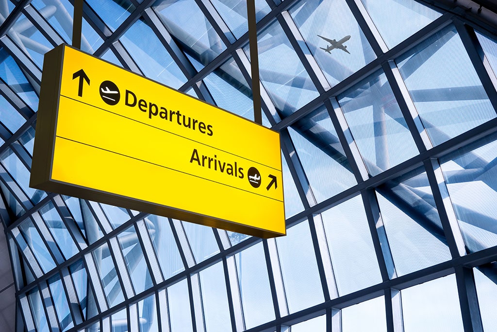 Large yellow airport sign for departures and arrivals with a glass background.