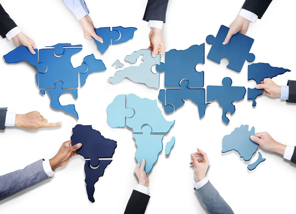  A group of hands all holding blue pieces of the globe that fit together if they work as a team.