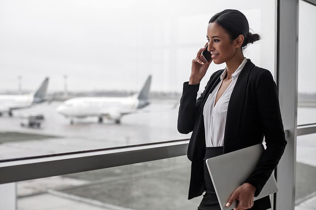 An airport operations manager having a phone call while standing next to a gate at the airport 