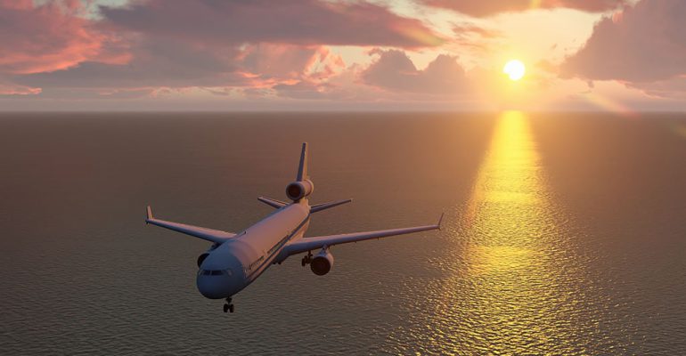 Airplane flying over water during a sunset.