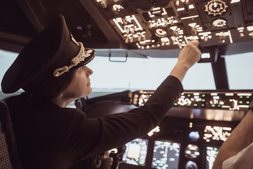 Uniformed female pilot within the plane prepares for take-off in the plane cockpit.