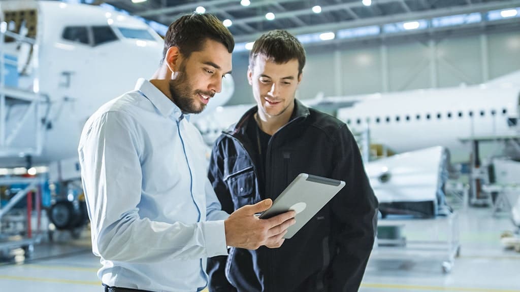 Aircraft Maintenance Worker and Engineer having Conversation while talking on a tablet