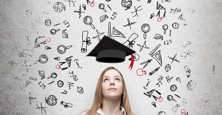 A young woman looks up at a graduation cap, wondering what the best business degree to get is