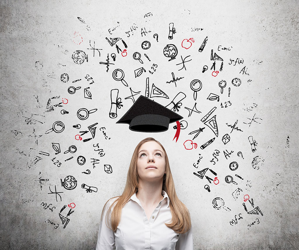 A young woman looks up at a graduation cap, wondering what the best business degree to get is