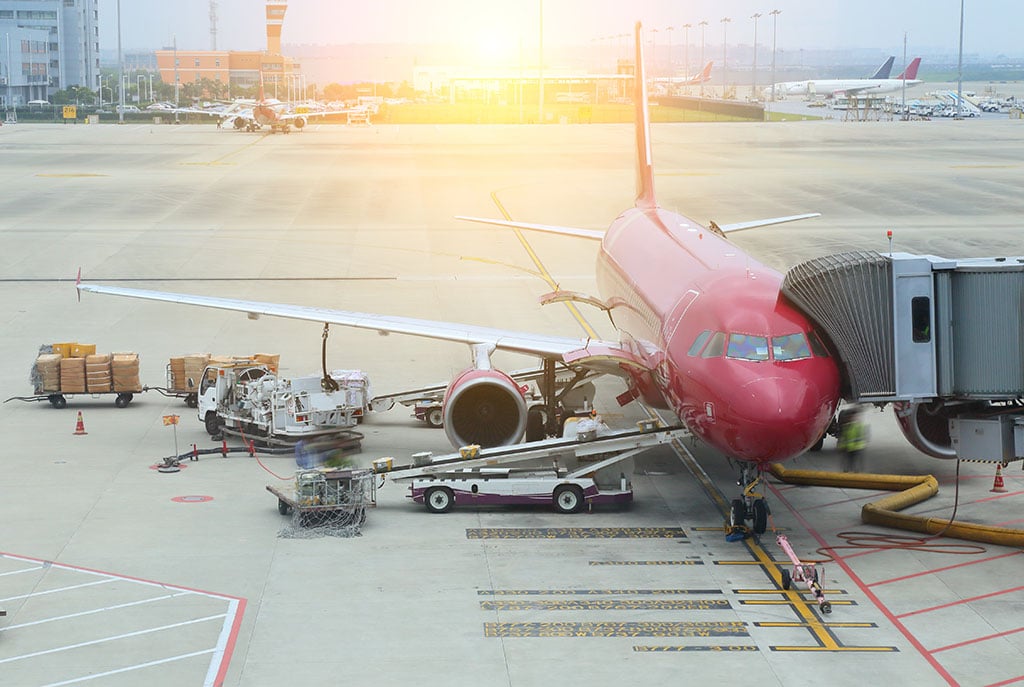 Passengers and luggage boarding a plane at a gate in an airport.