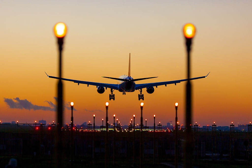 A plane landing with a sunset in the background