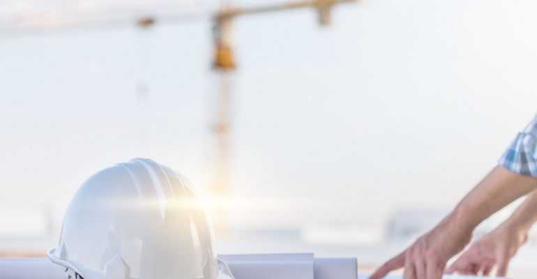 A surveying manager looking at plans on a table.