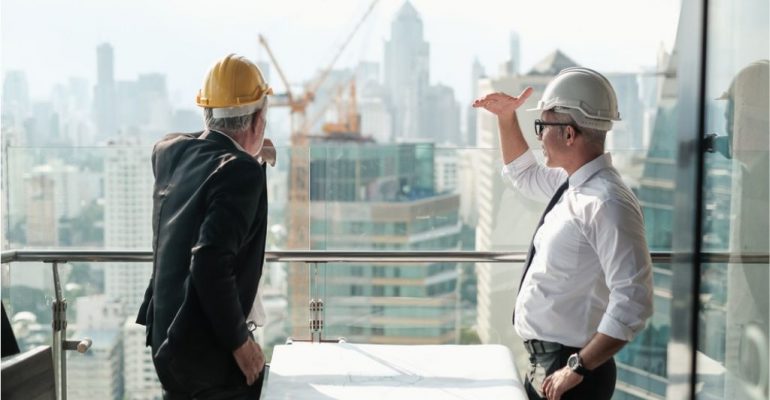 A construction manager discussing a project with his colleague at a construction site.