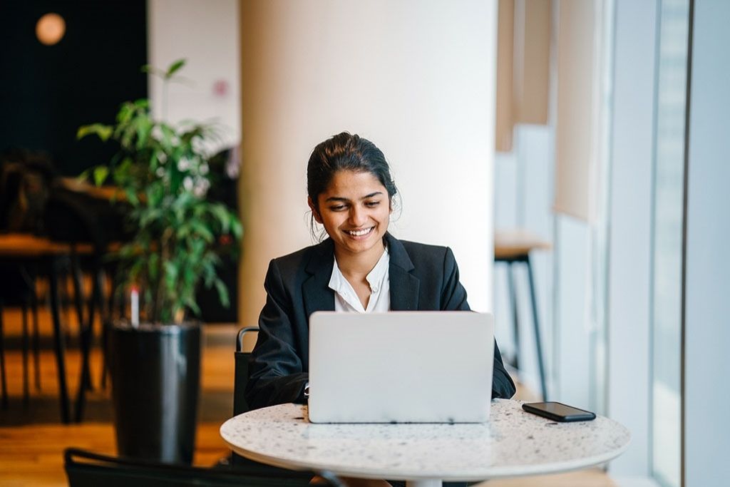 Female student uses a laptop at a table.