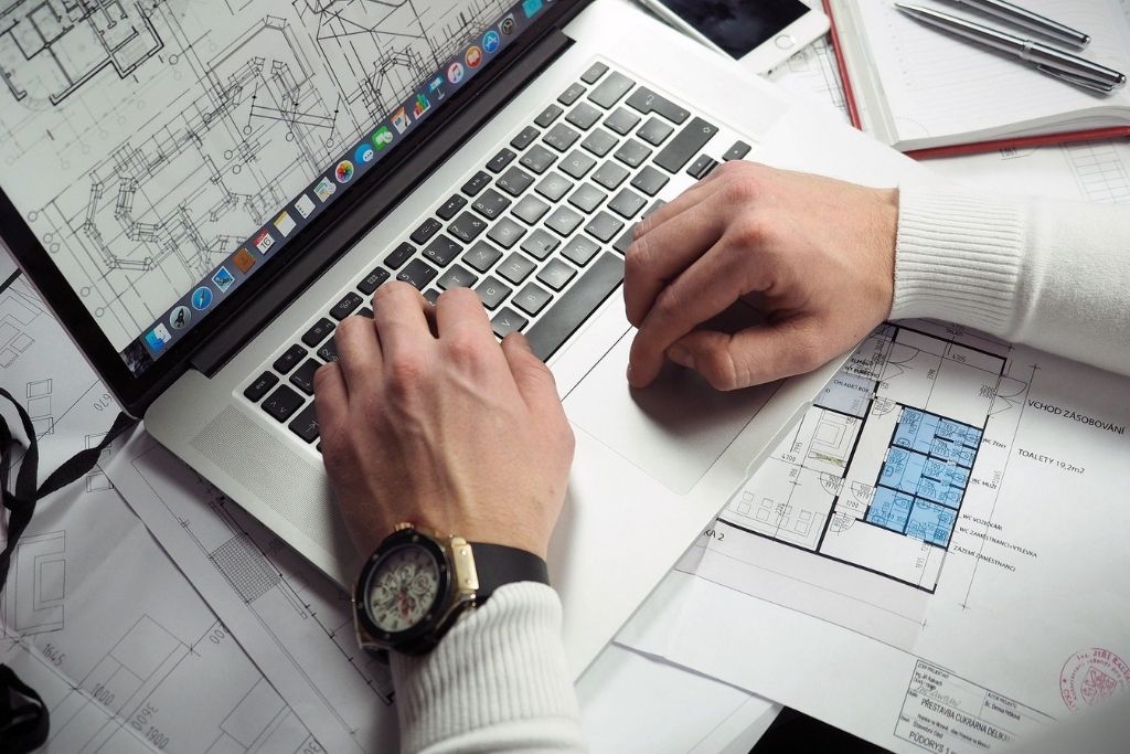 Entrepreneur uses a computer on a table full of reports.