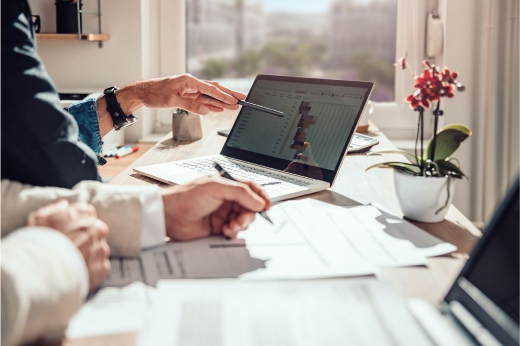 Businessmen reviewing project timelines on a laptop.