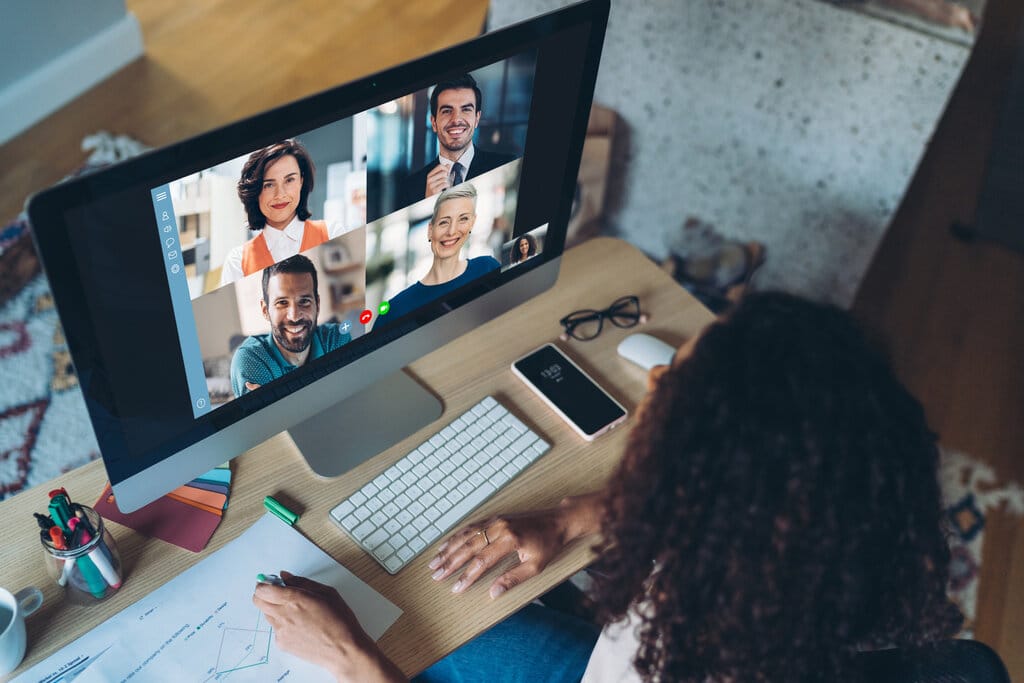 A businessperson who works at a multinational company meeting with her colleagues over a video.