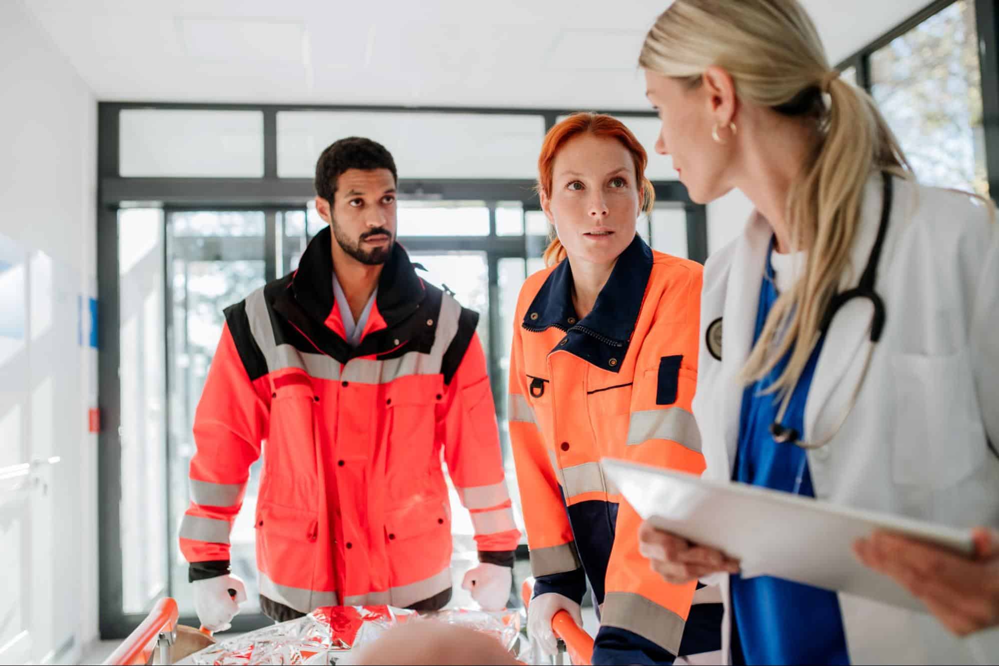 Emergency response professionals and a doctor coordinating care in a hospital setting as part of the disaster management cycle.