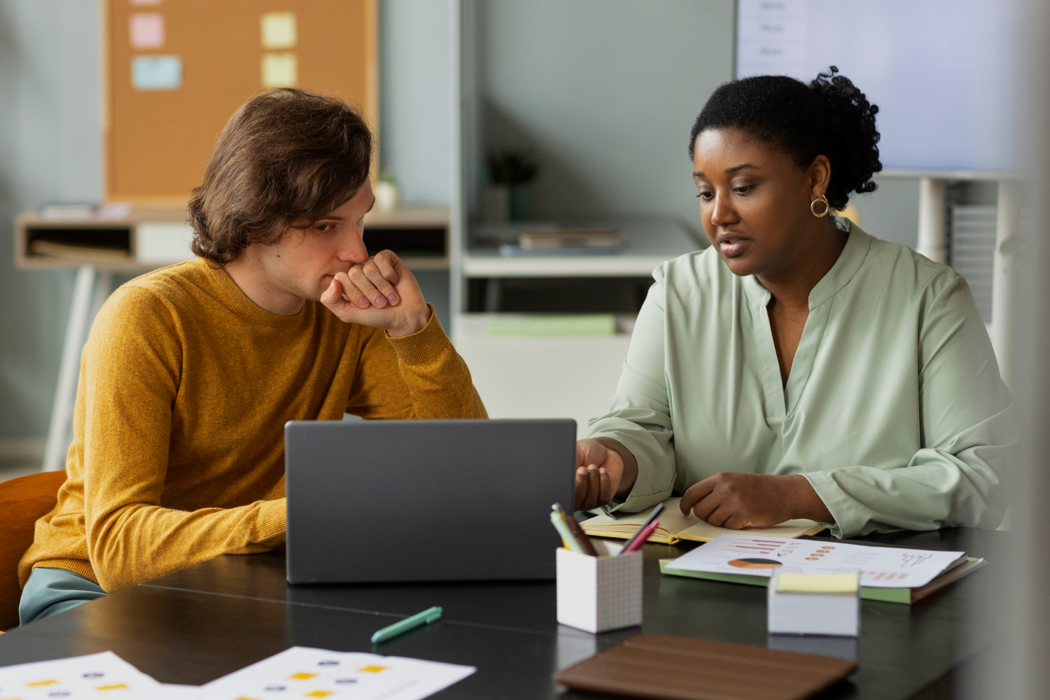 Colleagues utilizing critical thinking and problem-solving skills while analyzing data on a laptop, a key example of how soft skills complement technical expertise in business.