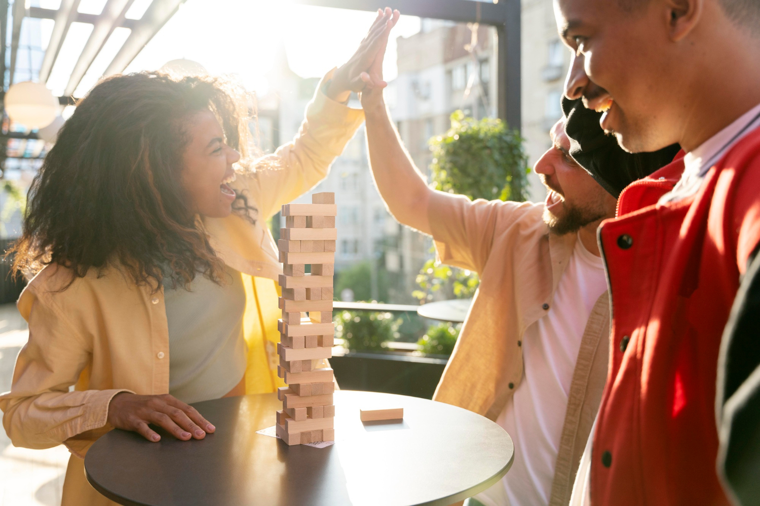 Enthusiastic coworkers high-fiving during a team-building game, illustrating how soft skills development fosters trust, teamwork, and positive office relationships.