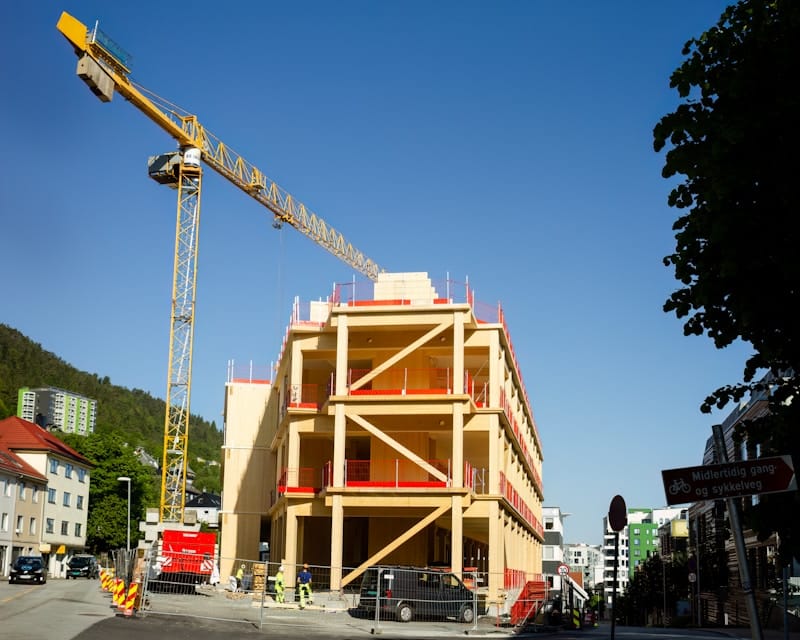 Crane lifting prefabricated modular building units into place for on-site assembly at urban construction project