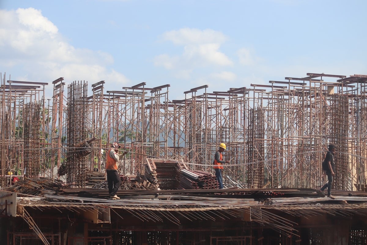 Workers on a modular construction building site assembling steel rebar framework on a permanent foundation