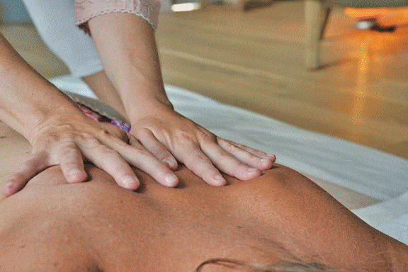 Massage therapist performing a back massage during an aromatherapy session