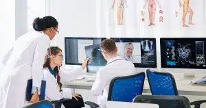 Clinicians reviewing medical scans on multiple screens in a diagnostics room