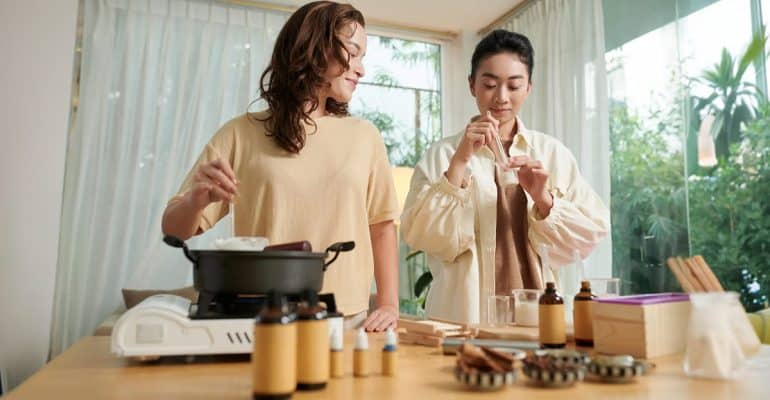 Two people preparing herbal remedies at a kitchen counter with essential oil bottles