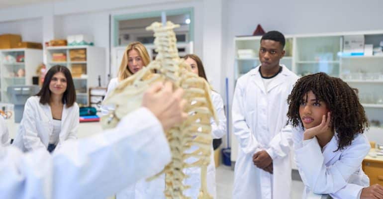 Students and an instructor examining a spine model in a laboratory