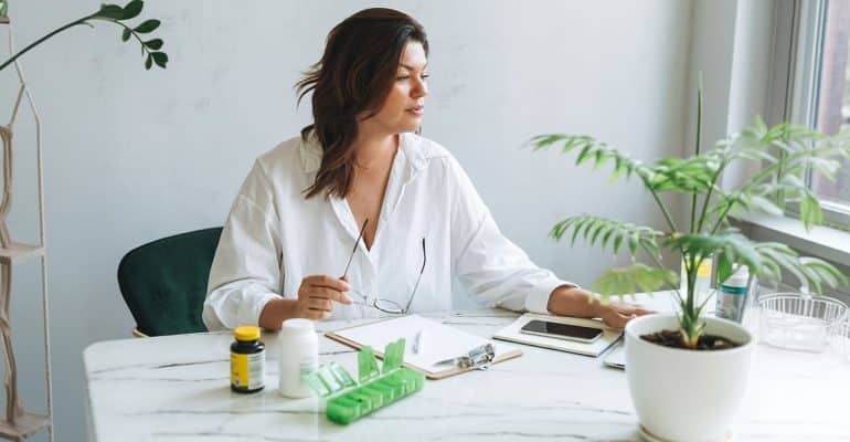 Naturopathic practitioner at a desk with plants and natural remedy bottles